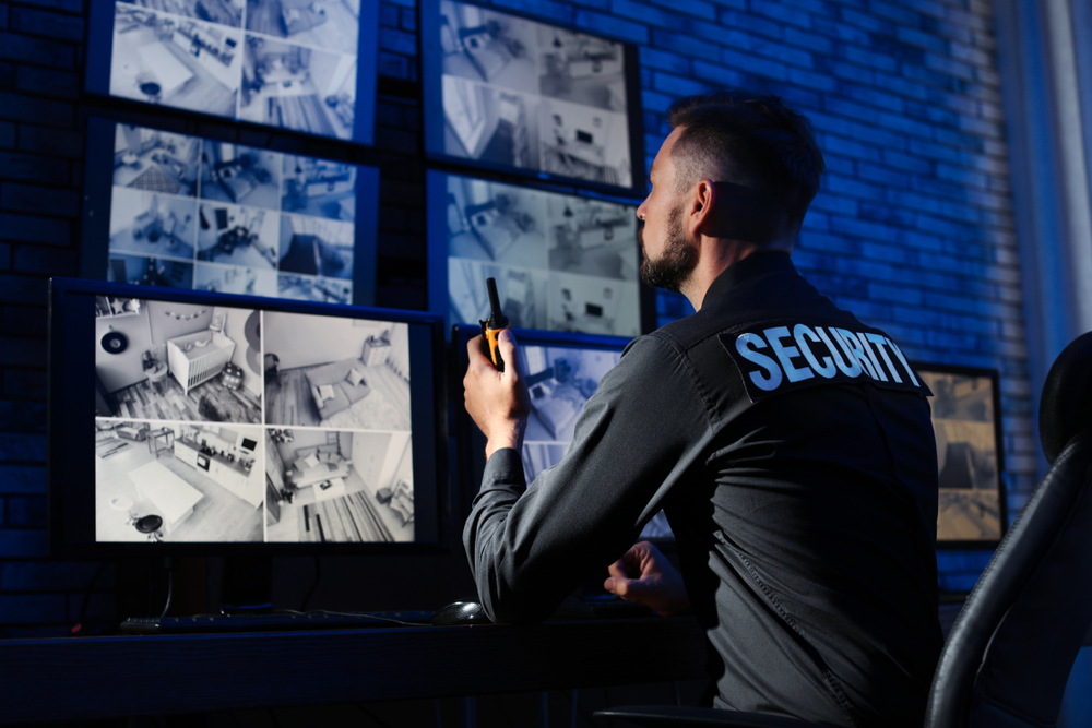 Male,security,guard,with,portable,transmitter,monitoring,modern,cctv,cameras